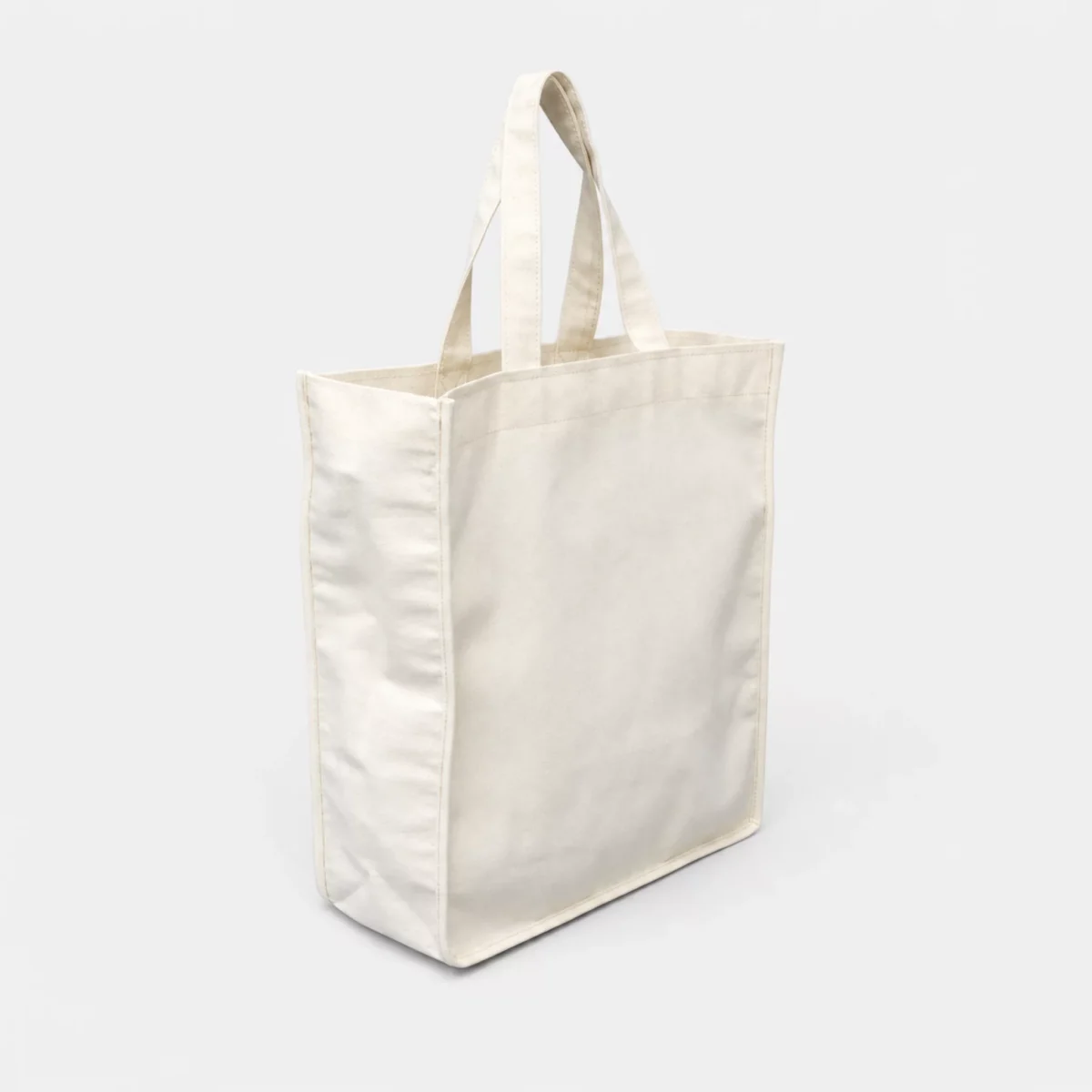 Bolsa chica de manta natural con fuelle, asas y bies perimetral sobre fondo gris claro